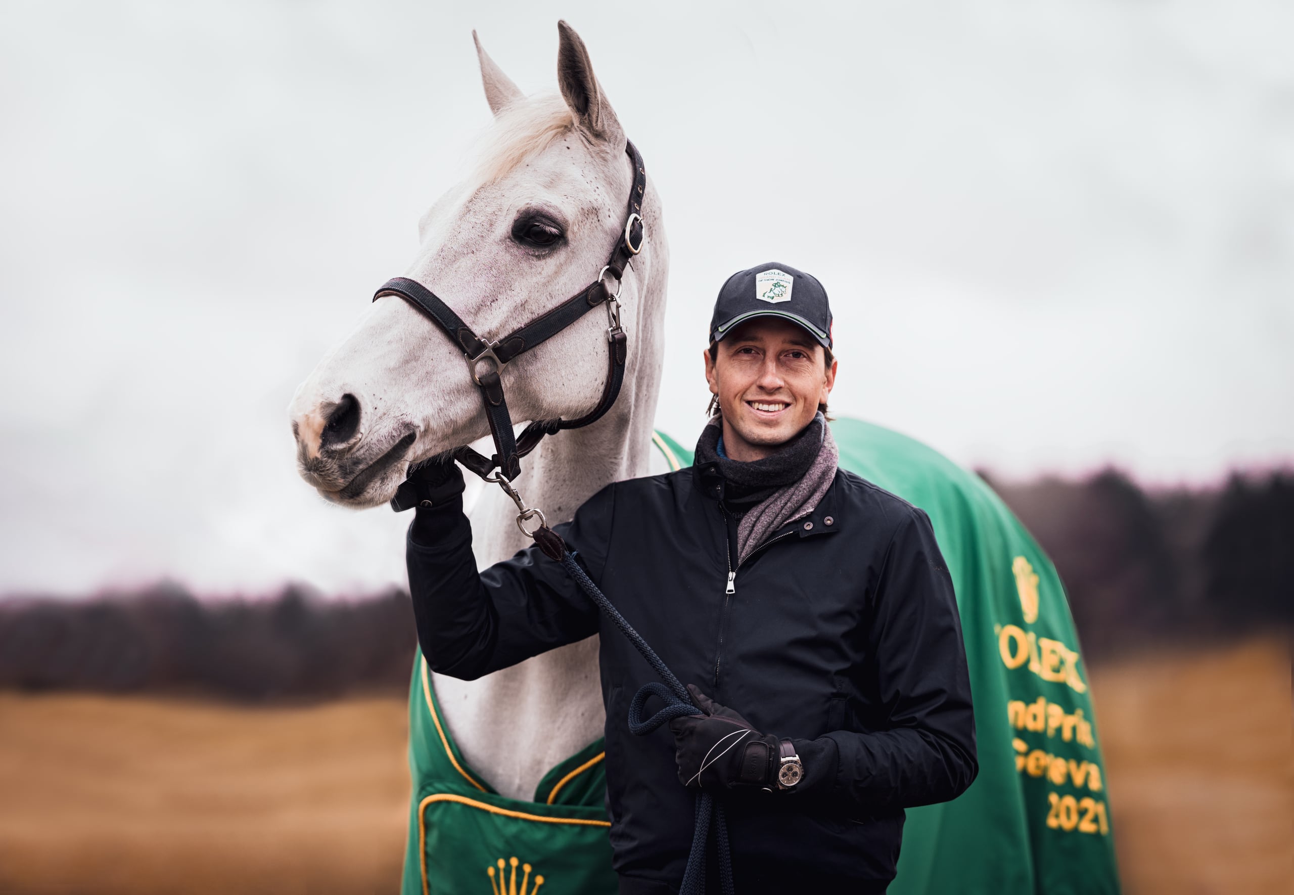Martin Fuchs standing next to Leone Jei, a grey horse